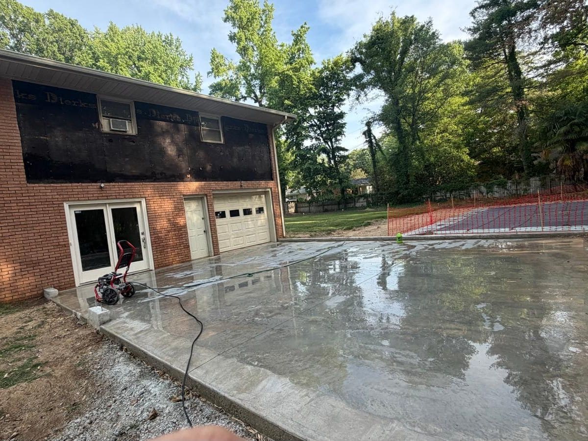 Exterior renovation with newly poured concrete driveway and siding work